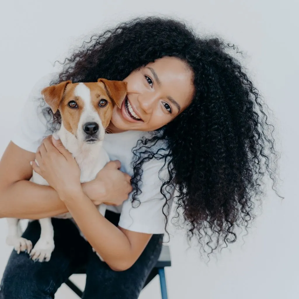 A smiling woman holding a Jack Russell terrier